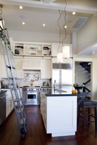 A ladder in the middle of a kitchen with white cabinets.