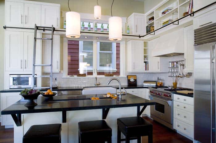 A kitchen with white cabinets and black island