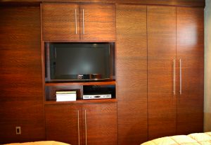 A bedroom with a television and wooden cabinets