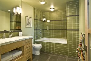 A bathroom with green tiles and white fixtures