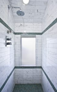 A bathroom with marble walls and green tile.