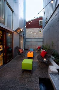 A patio with chairs, tables and lights in it.