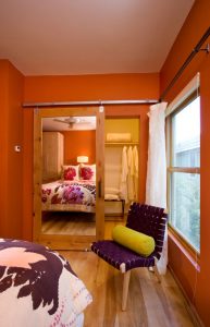 A bedroom with orange walls and a bed in the corner.