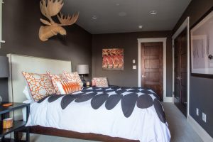A bedroom with a bed and two moose heads on the wall