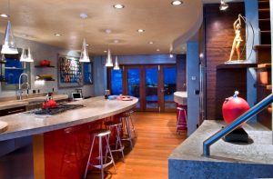 A kitchen with red and blue walls, wooden floors and a large island.